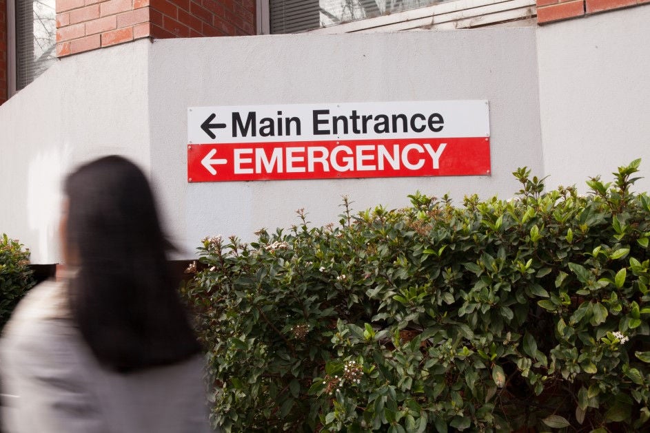 a woman walks past a hospital emergency sign