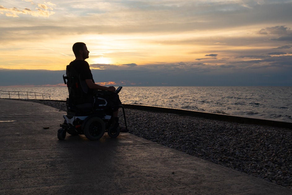 A man in wheelchair by the beach