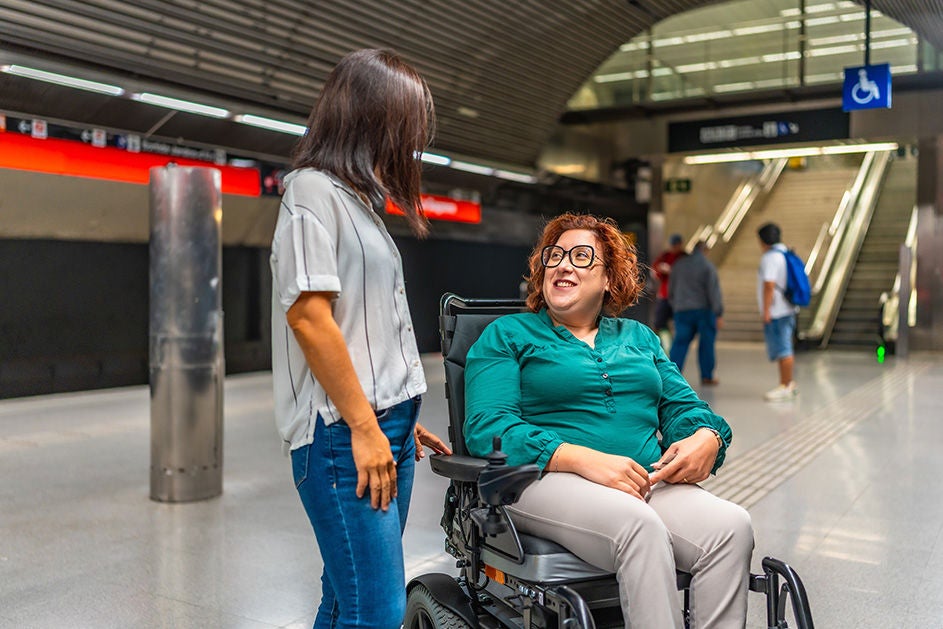 A woman talking to another woman sitting on the wheelchair