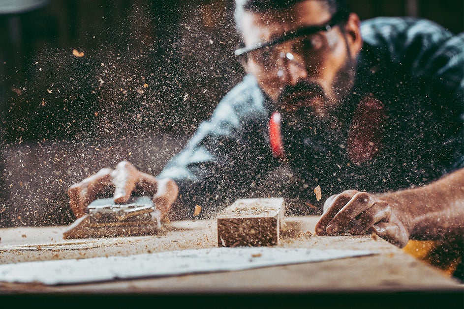 A man sanding a wooden table