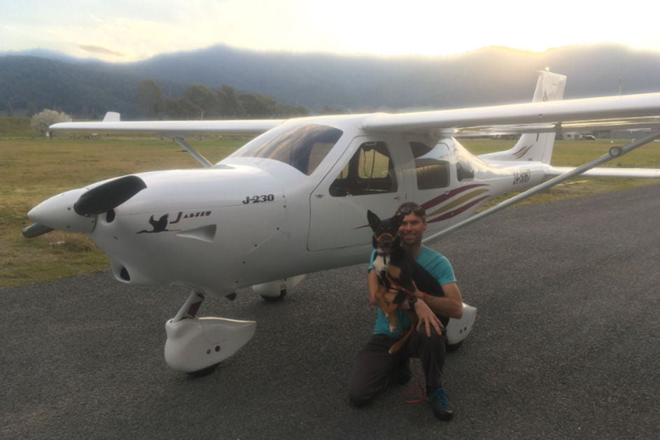 Mathew with his dog, standing next to a plane