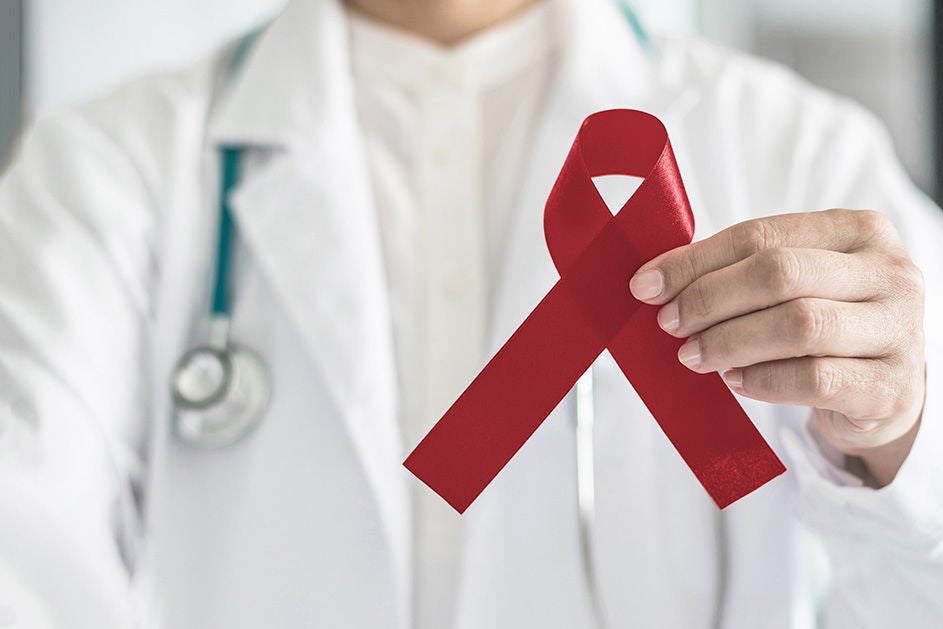 A healthcare professional holds a red ribbon