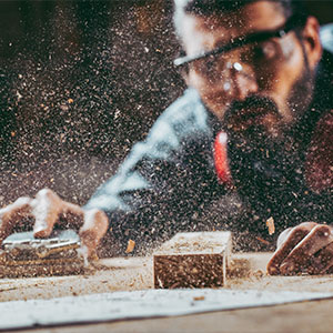 A man sanding a wooden table