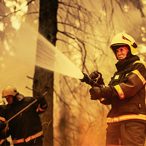 A female firefighter uses a water hose to control a bushfire