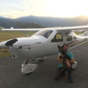 Mathew with his dog, standing next to a plane