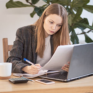 Woman sitting at a desk in the office, writing down notes